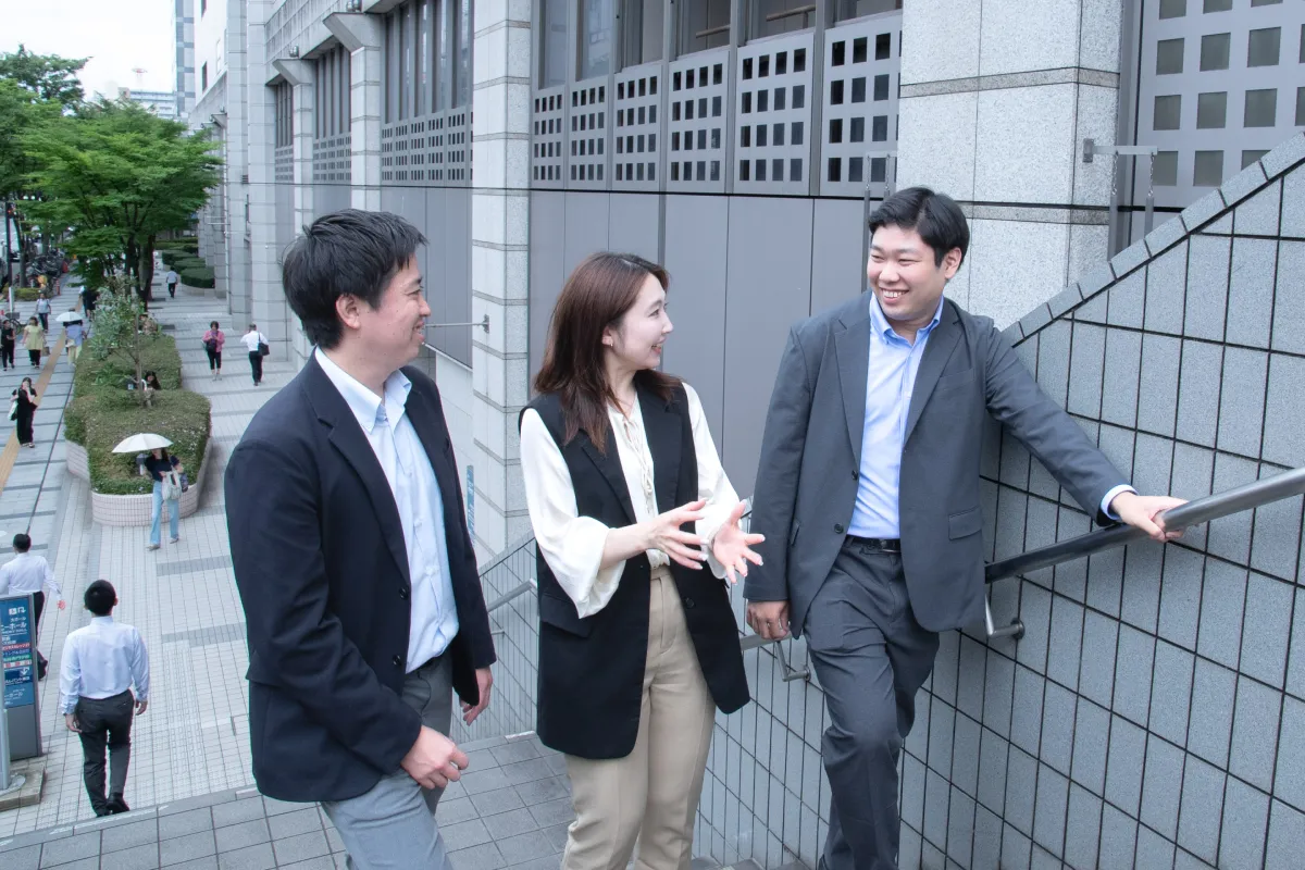 外で和やかに会話する3名の社員